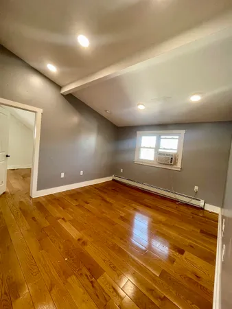 a view of empty room with window and wooden floor