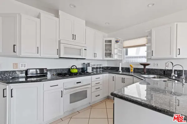 a kitchen with granite countertop white cabinets and white appliances