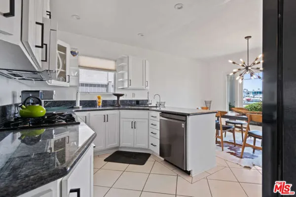 a kitchen with stainless steel appliances granite countertop a sink counter space cabinetry and a chandelier