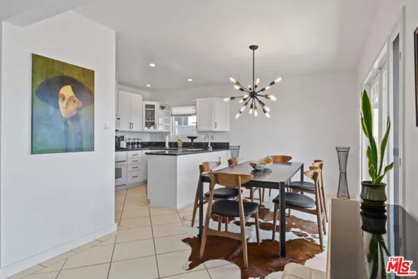 a dining room filled a chandelier and kitchen view