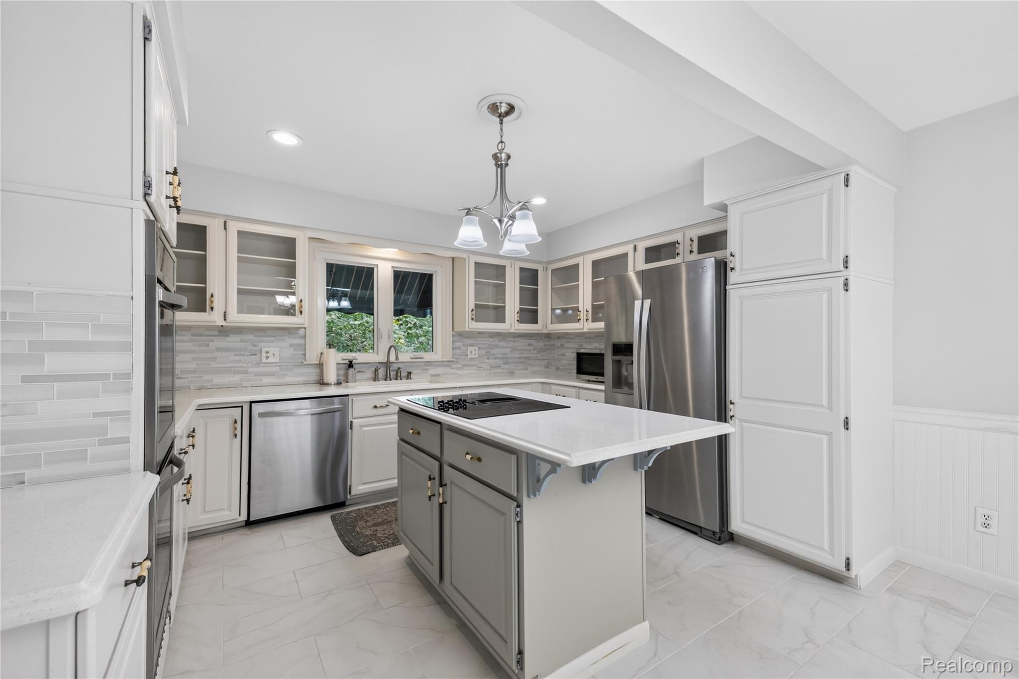 25645 Meridian Road Grosse Ile, MI 48138 - Photo 9 of 46 Updated kitchen featuring white shaker cabinetry, stainless steel appliances, a center island with cooktop, and light-toned tile flooring