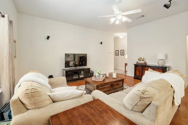 a living room with furniture a flat screen tv and a ceiling fan
