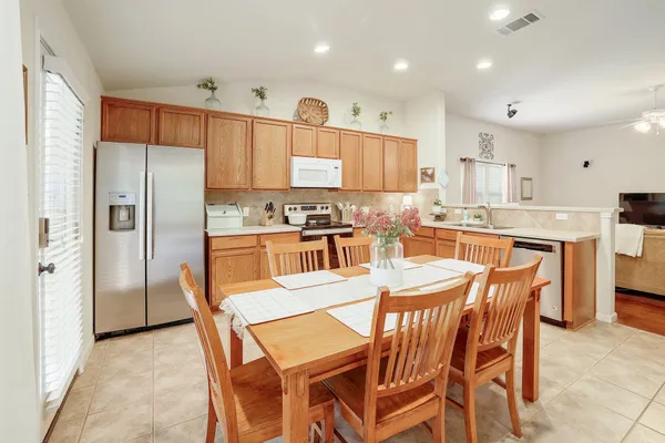a kitchen with a dining table chairs refrigerator and cabinets
