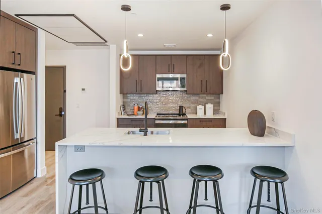 a kitchen with stainless steel appliances a table chairs refrigerator and sink