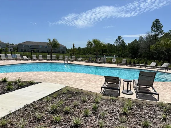 a swimming pool with outdoor seating and yard in back