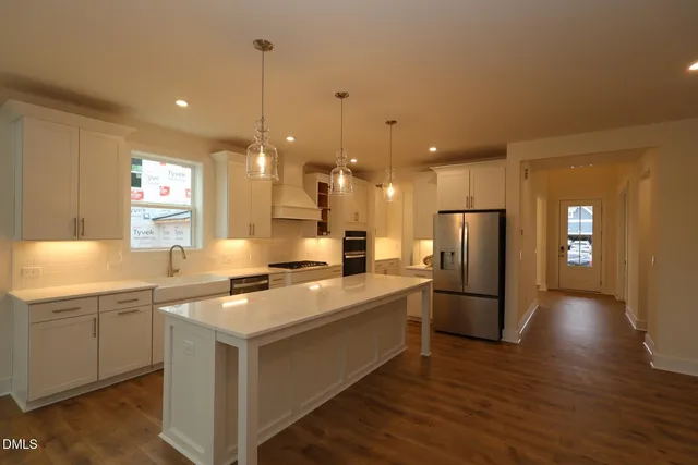 a large kitchen with stainless steel appliances a large counter top a sink and a refrigerator