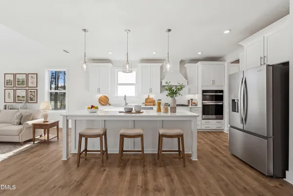 a kitchen with stainless steel appliances a sink a stove a refrigerator and island with wooden floor