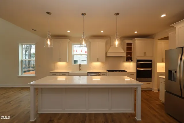 a kitchen with a refrigerator a sink and wooden floor