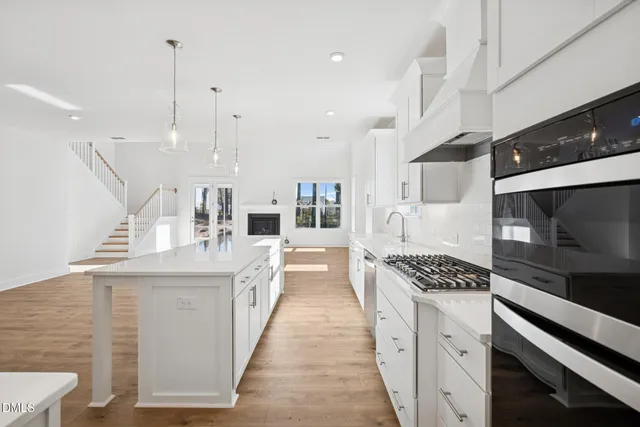 a kitchen with stainless steel appliances a sink a stove a refrigerator and island with wooden floor
