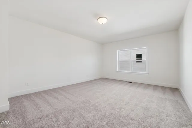 a view of an empty room with wooden floor and a fireplace