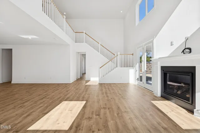 a view of an empty room with wooden floor fireplace and a window