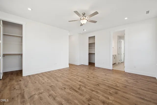 a view of an empty room with a window and wooden floor
