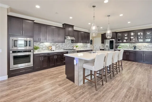 a kitchen with stainless steel appliances granite countertop a table chairs sink refrigerator and cabinets