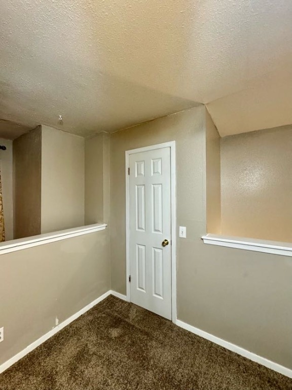 1305 West Villa Maria Road, Unit F105 Bryan, TX 77801 - Photo 15 of 26 Unfurnished room featuring dark colored carpet and a textured ceiling