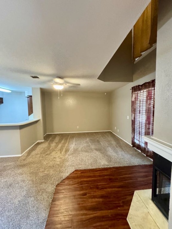 1305 West Villa Maria Road, Unit F105 Bryan, TX 77801 - Photo 4 of 26 Unfurnished living room with dark colored carpet, a multi sided fireplace, ceiling fan, and dark wood-type flooring