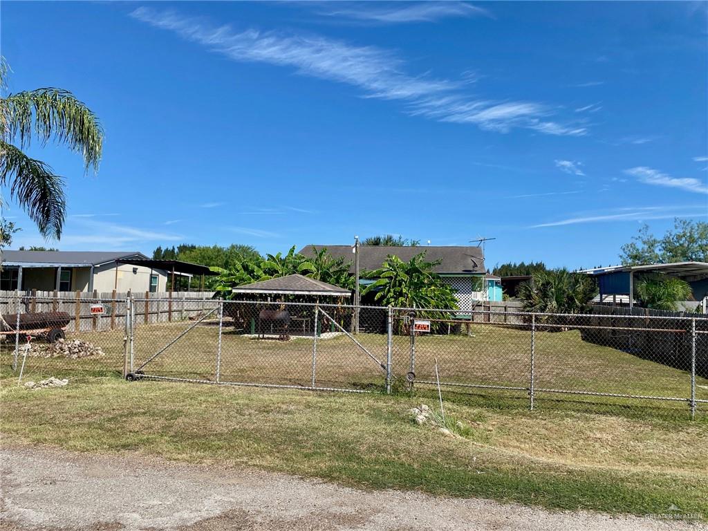 Chain-link fence with a double-gate entry, offering a private outdoor space with a gazebo and established trees