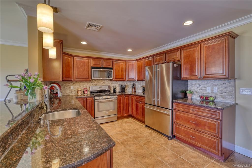 a kitchen with stainless steel appliances granite countertop a refrigerator sink stove microwave and cabinets