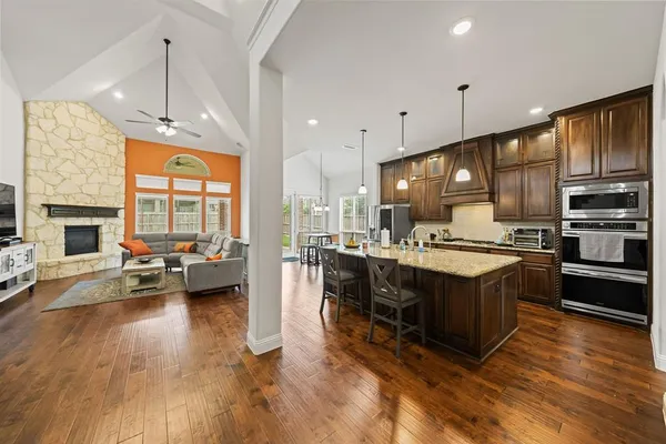 a kitchen with stainless steel appliances granite countertop a stove and a view of living room with furniture
