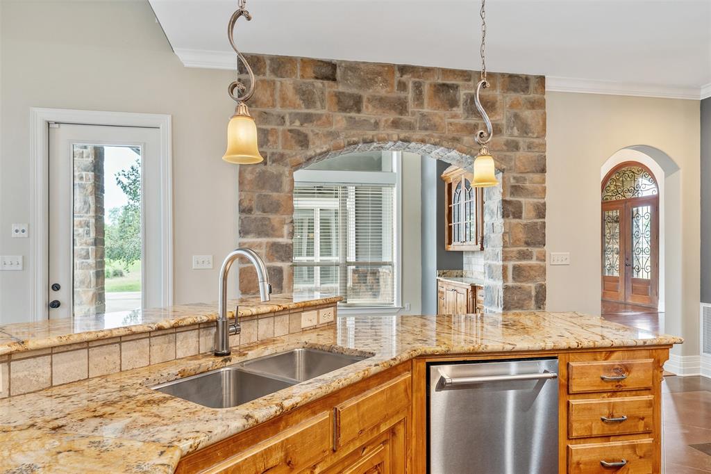 20389 County Road 178 Flint, TX 75762 - Photo 7 of 40 Kitchen island featuring a double basin stainless steel sink, granite countertop, and tiled backsplash