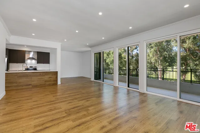 a large kitchen with stainless steel appliances a large counter top a stove a sink and a refrigerator