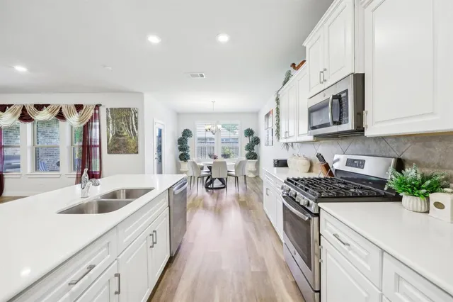 a kitchen with stainless steel appliances a sink dishwasher stove microwave and cabinets with wooden floor