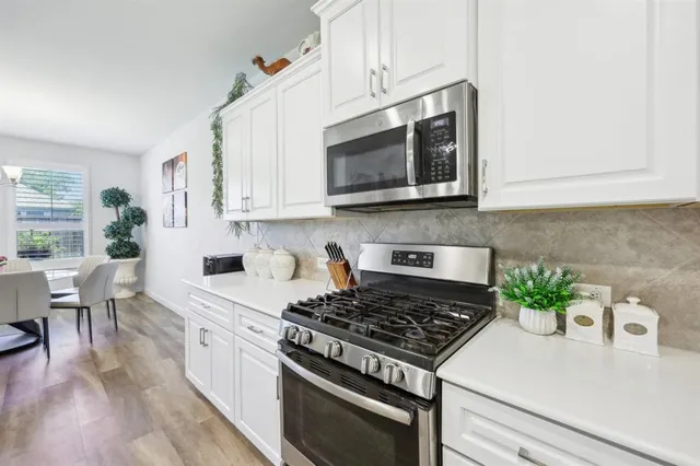 a kitchen with stainless steel appliances white cabinets and a stove top oven