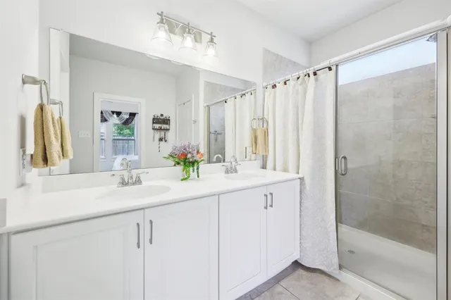 a bathroom with a double vanity sink mirror and shower