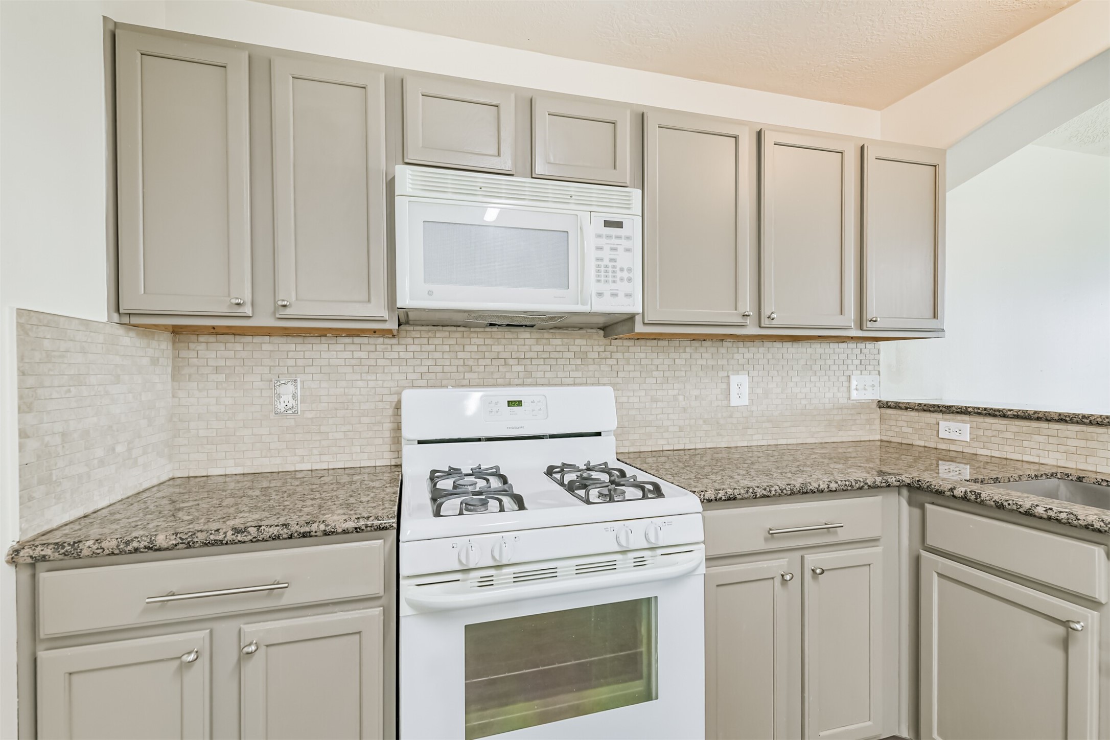2415 Fox River Lane Spring, TX 77386 - Photo 9 of 34 a kitchen with granite countertop white cabinets and white appliances