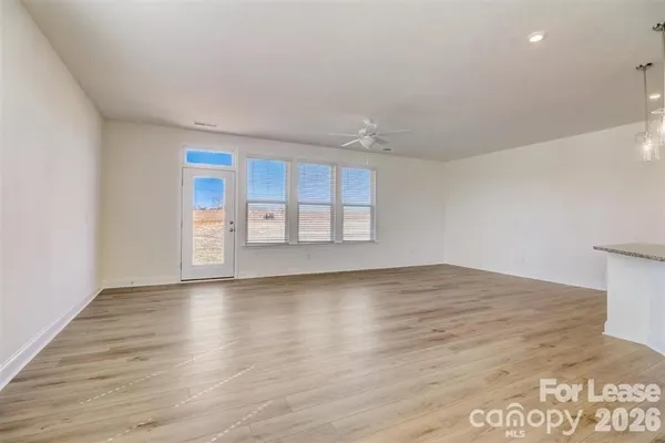 a view of an empty room with window and wooden floor