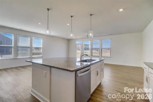 a kitchen with stainless steel appliances granite countertop a sink a stove and a wooden floors