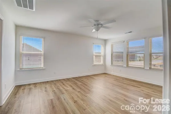 a view of an empty room with a window and wooden floor