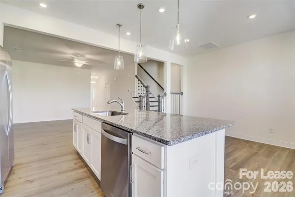 a kitchen with stainless steel appliances granite countertop a sink a stove and a wooden floors