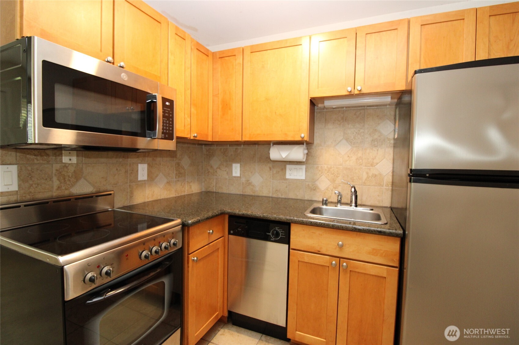 604 North 3rd Street, Unit 7 Tacoma, WA 98403 - Photo 8 of 12 a kitchen with stainless steel appliances a stove a microwave sink and cabinets