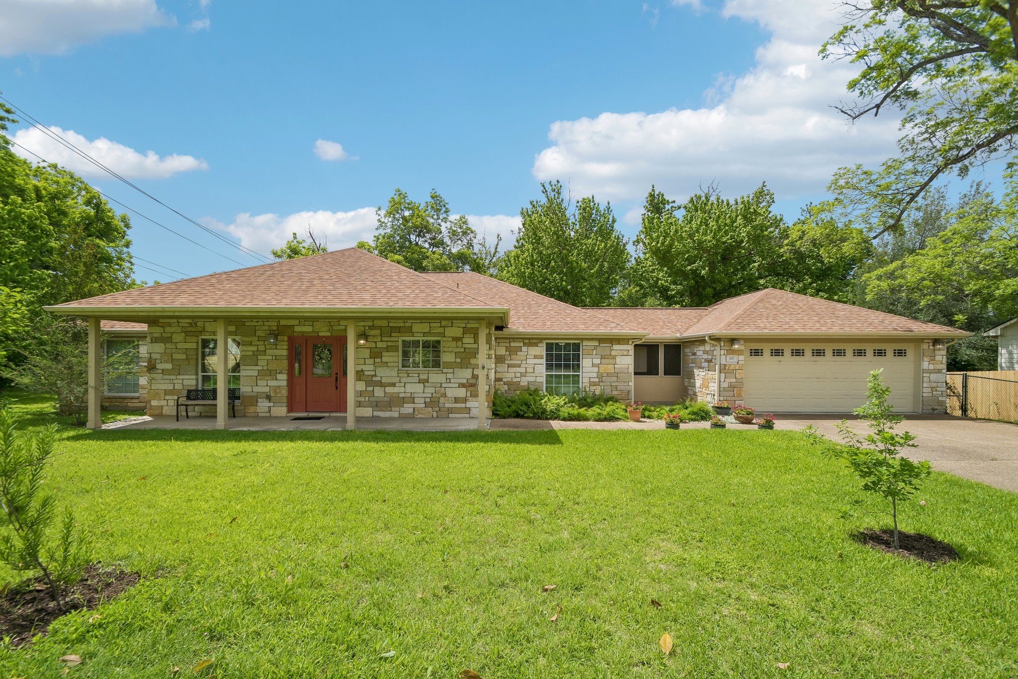 307 West 4th Street Elgin, TX 78621 - Photo 1 of 40 Stone veneer exterior with a covered porch, a red front door, and a two-car garage