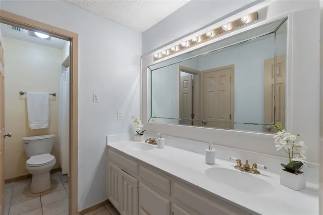 a spacious bathroom with a granite countertop sink a toilet and a mirror
