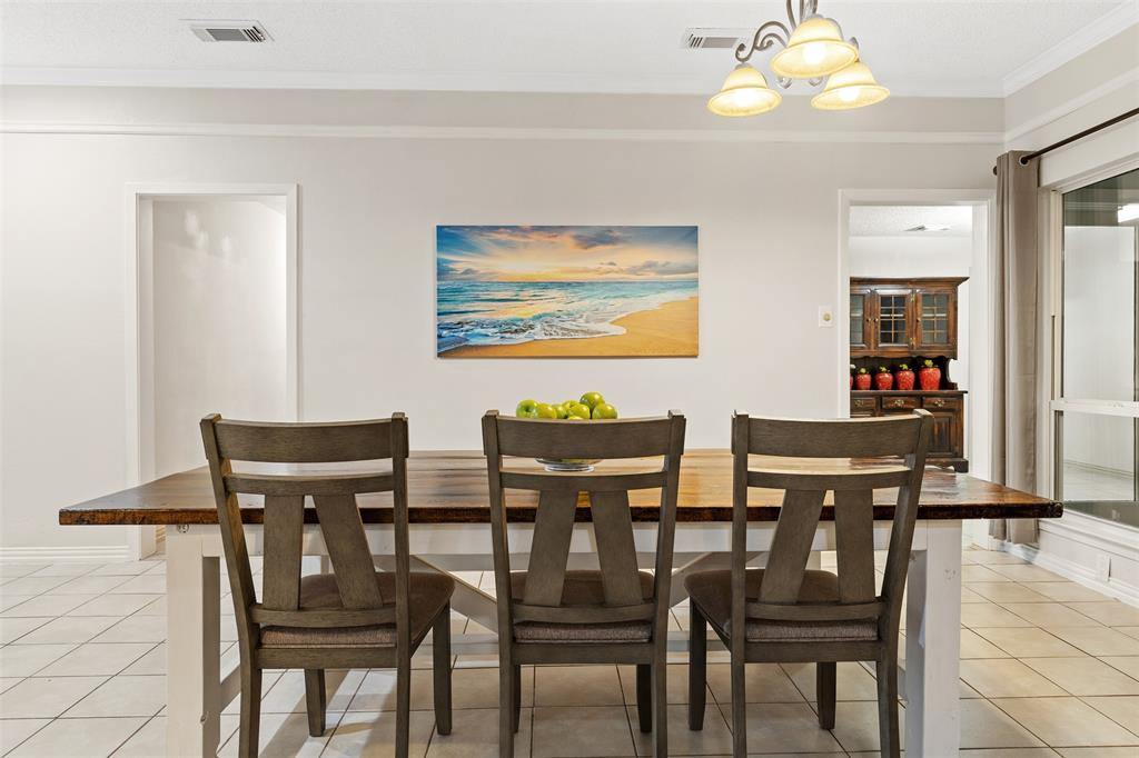 1105 East Spring Valley Road Richardson, TX 75081 - Photo 3 of 40 Dining area featuring light tile patterned flooring, visible vents, an inviting chandelier, and crown molding