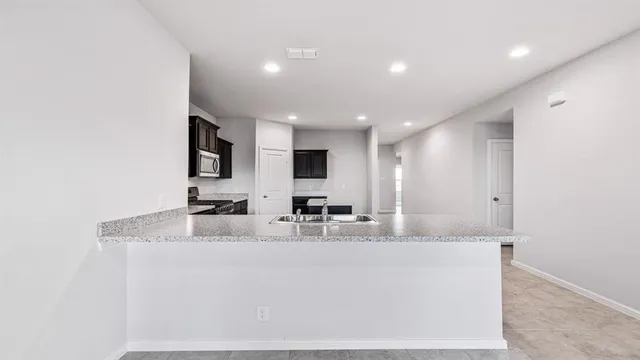 a kitchen with kitchen island a sink and a stove top oven with wooden floor