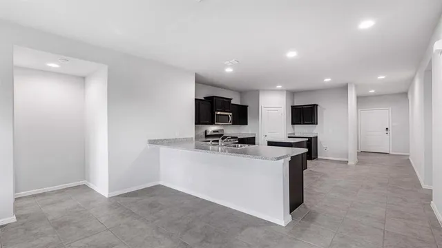 a view of a kitchen with kitchen island stainless steel appliances a sink stove and refrigerator