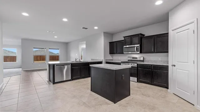 a kitchen with stainless steel appliances granite countertop a stove top oven a sink dishwasher a dining table and chairs with wooden floor