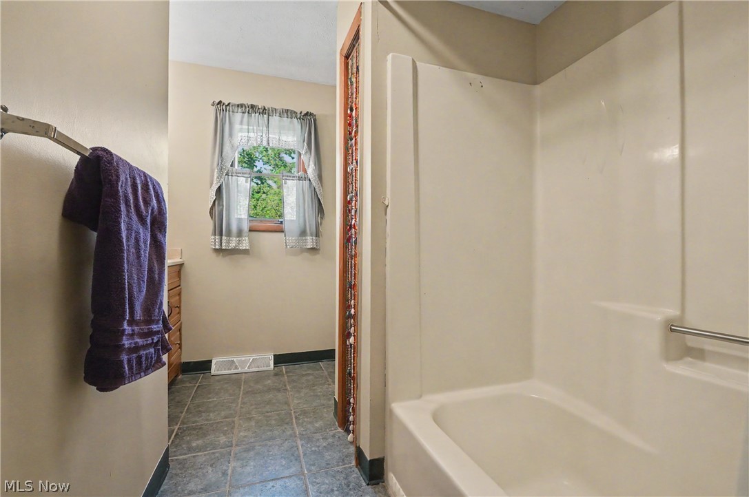 4250 Herr Fieldhouse Road Southington, OH 44470 - Photo 12 of 50 Bathroom featuring a tub/shower combination, tile flooring, a window, and a built-in vanity with cabinetry