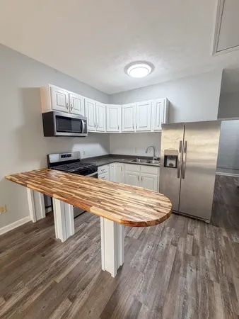 a kitchen with kitchen island wooden floors appliances and refrigerator