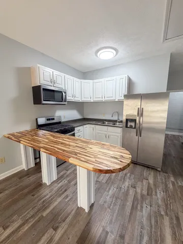 a kitchen with kitchen island wooden floors appliances and refrigerator