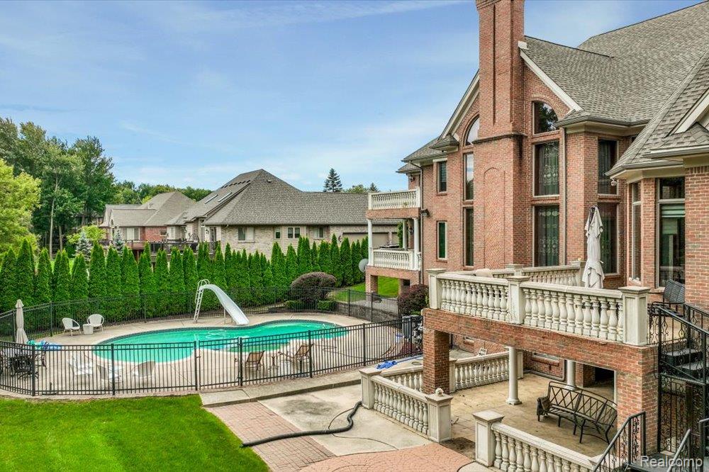3543 Cedar Brook Drive Rochester, MI 48309 - Photo 92 of 99 Brick exterior featuring multiple levels of balconies, an exterior spiral staircase, and a large inground pool with surrounding hardscaping