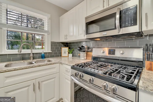 a kitchen with stainless steel appliances granite countertop white cabinets and window