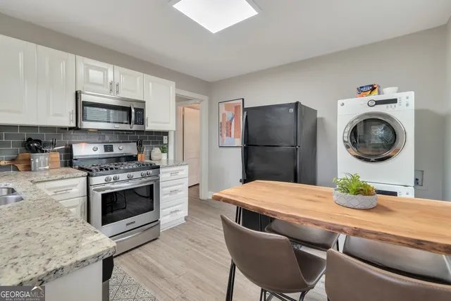 a kitchen with stainless steel appliances a stove a refrigerator a dining table and chairs