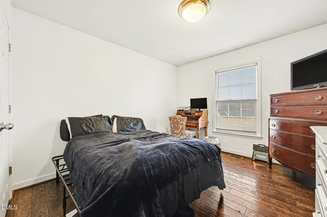 a bedroom with a bed a flat screen tv and a window