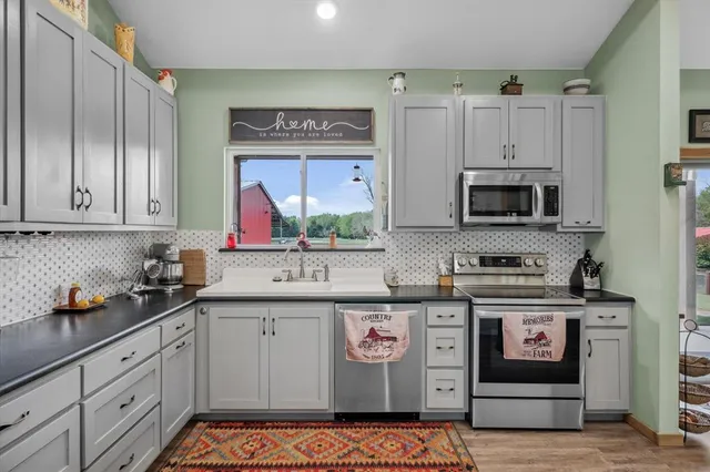 a kitchen with stainless steel appliances granite countertop a stove a sink and a microwave