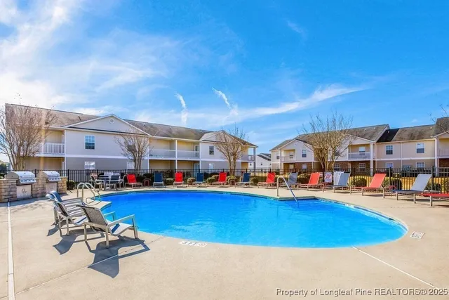 a view of a swimming pool with lawn chairs and potted plants