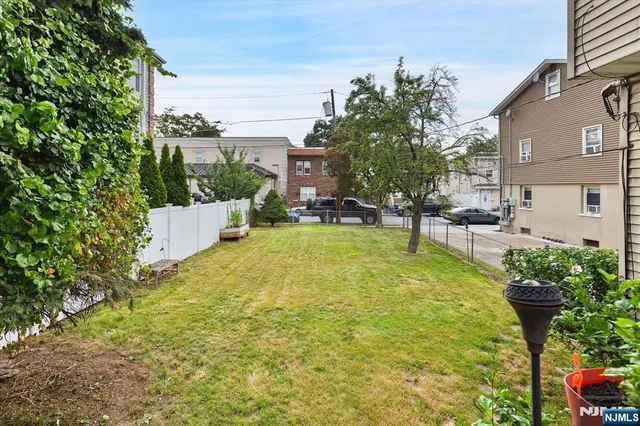 a view of a backyard with table and chairs a barbeque and a large trees