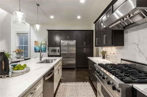 a open kitchen with stainless steel appliances granite countertop a stove a sink dishwasher a refrigerator and a dining table with wooden floor